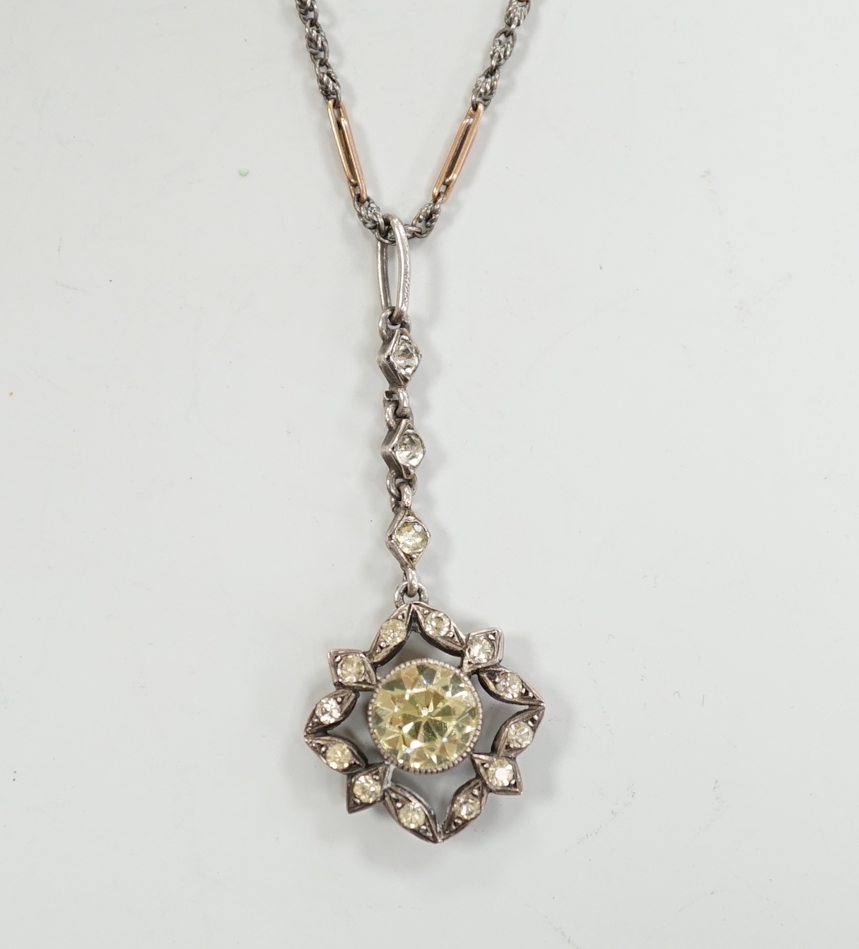 A 19th century white metal and foil backed paste set pendant, 40mm, on a later two colour chain, the clasp stamped 9ct.